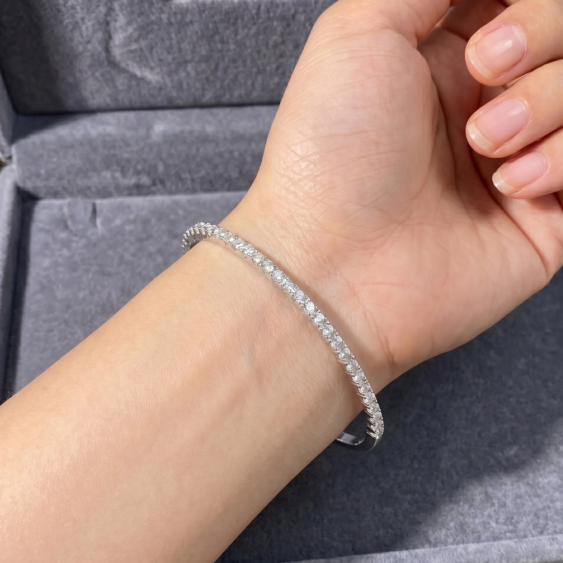 2.5mm moissanite half tennis bangle bracelet in 925 sterling silver worn on hand showing half-set stone design and plain silver underside - Sensitive Stones
