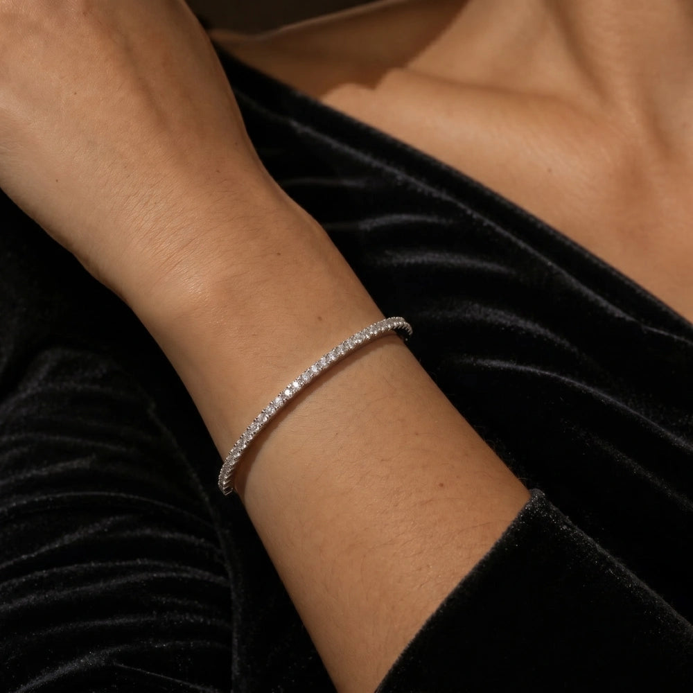 White gold moissanite half tennis bangle bracelet worn on wrist with black velvet dress, 2.5mm stones in 925 sterling silver - Sensitive Stones