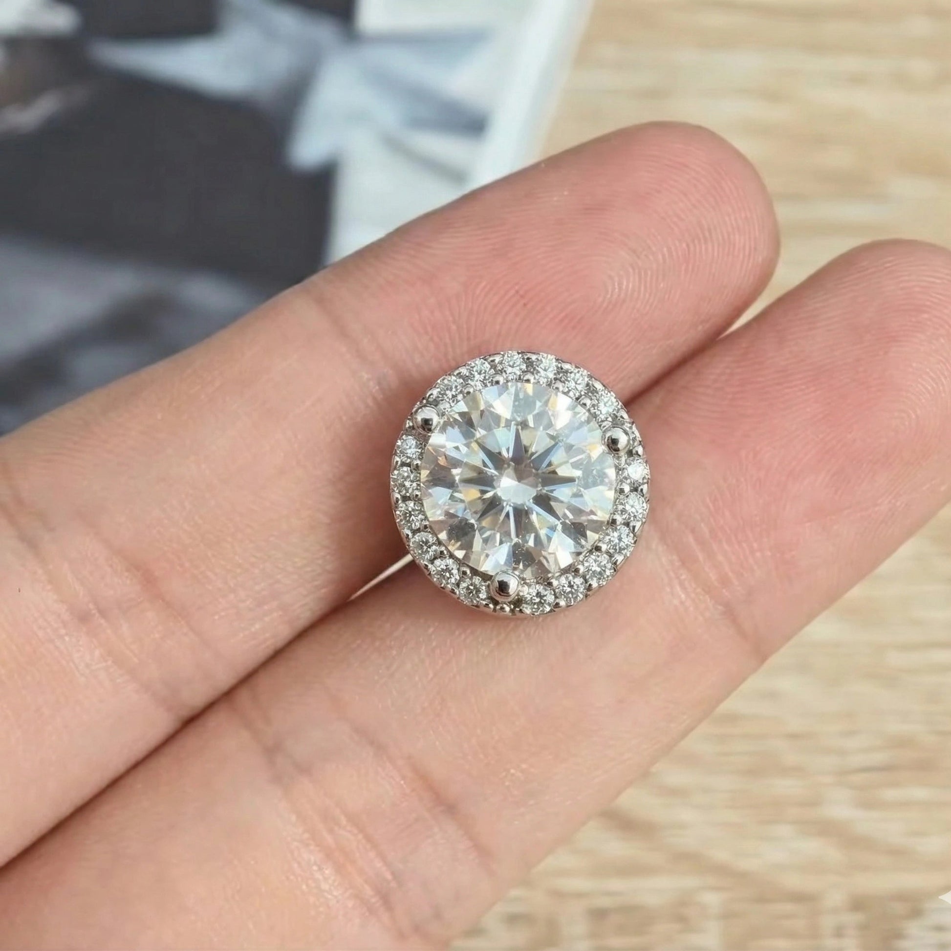  Round moissanite halo stud earring held in hand showing brilliant D color VVS1 center stone with cubic zirconia accent halo - Sensitive Stones