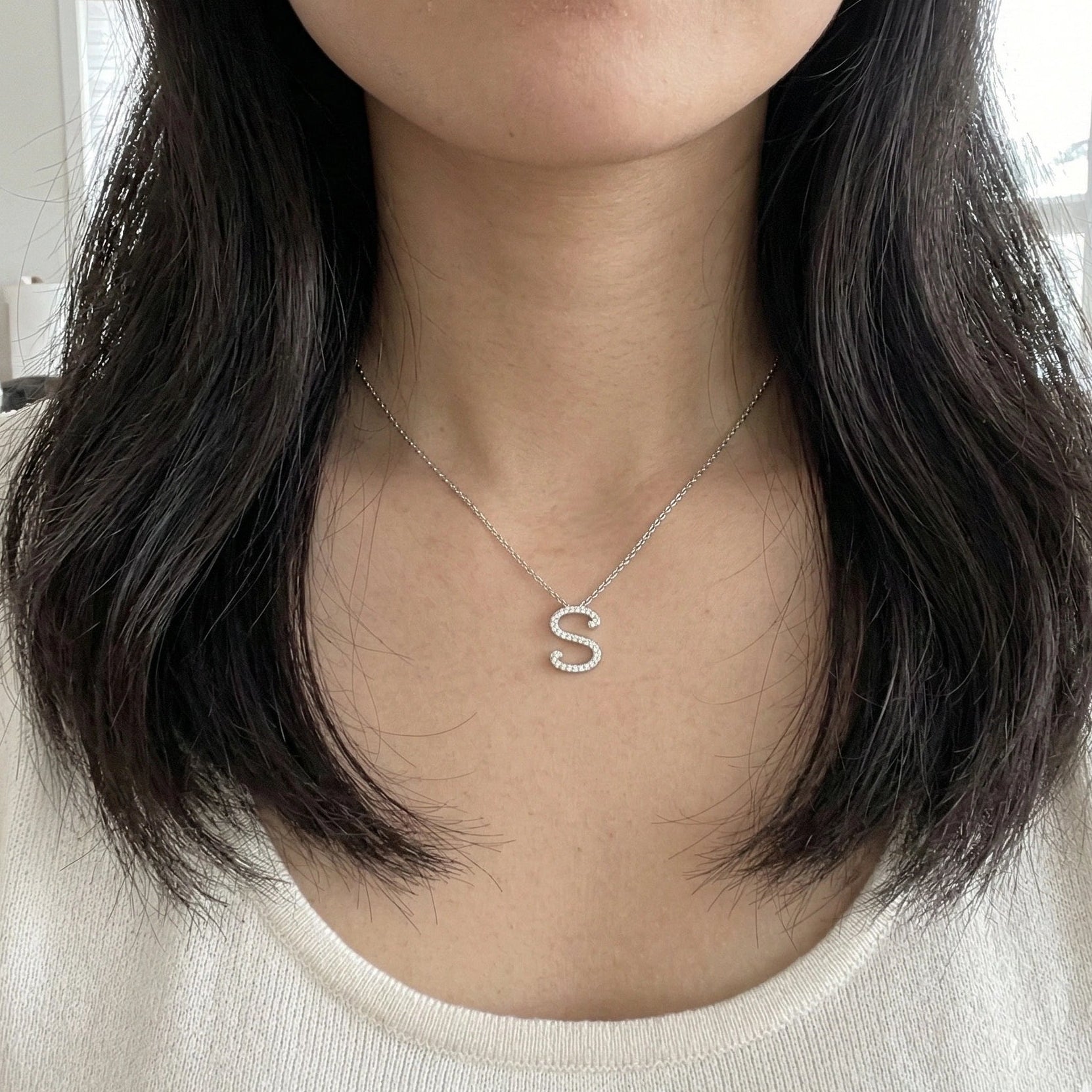 Moissanite initial necklace letter S worn by Asian model cream top natural window light - Sensitive Stones