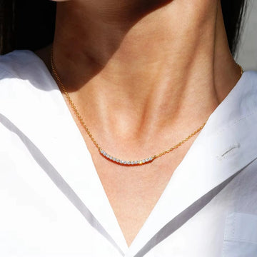 Woman wearing moissanite curved bar necklace in 18K yellow gold plated 925 silver at collarbone - Sensitive Stones