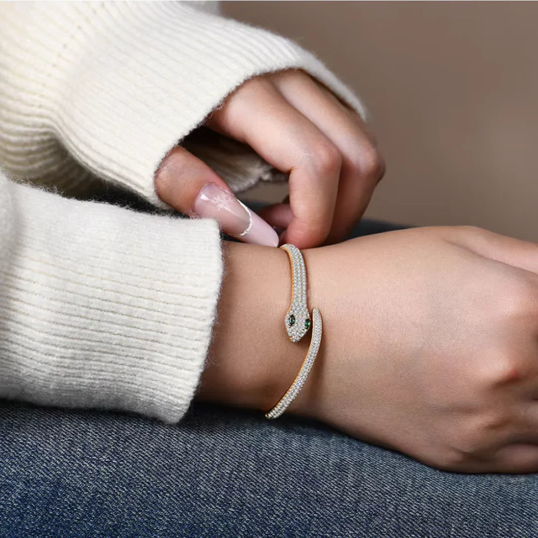 Elegant moissanite snake bracelet in gold with green gemstone eyes styled on wrist | Sensitive Stones