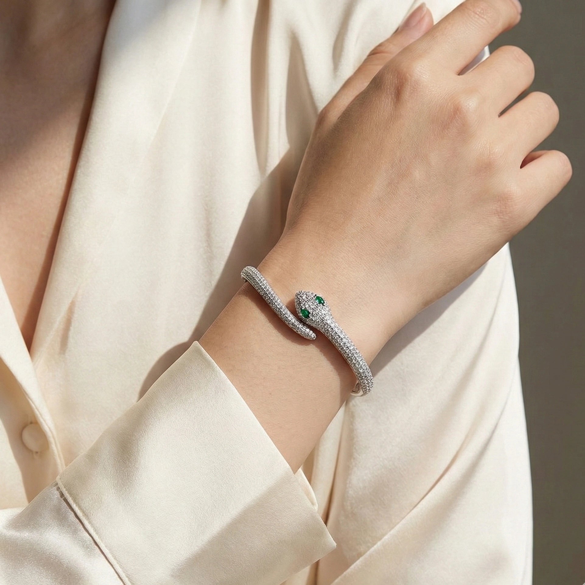 Elegant moissanite snake bracelet in silver with green gemstone eyes styled on wrist - Sensitive Stones