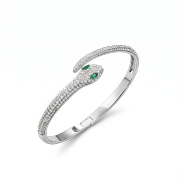 Moissanite snake bracelet in 925 sterling silver with a white gold finish, a pavé serpent hinged bangle with green lab-created emerald eyes, on a white background - Sensitive Stones