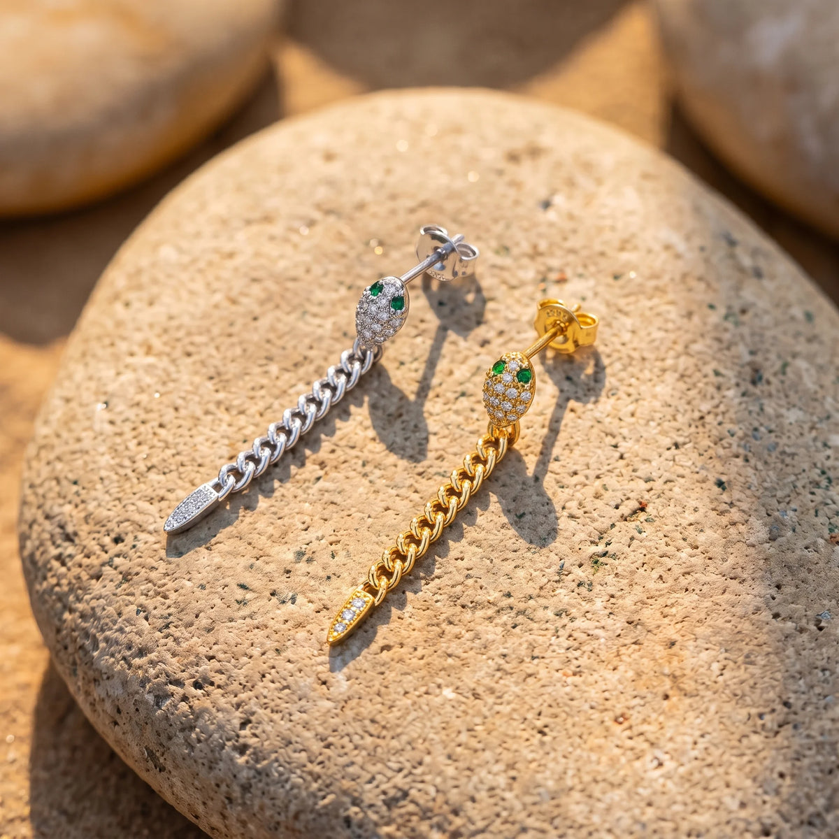 Moissanite snake chain drop earrings in white gold and yellow gold finishes side by side on a stone, showing the butterfly backs - Sensitive Stones