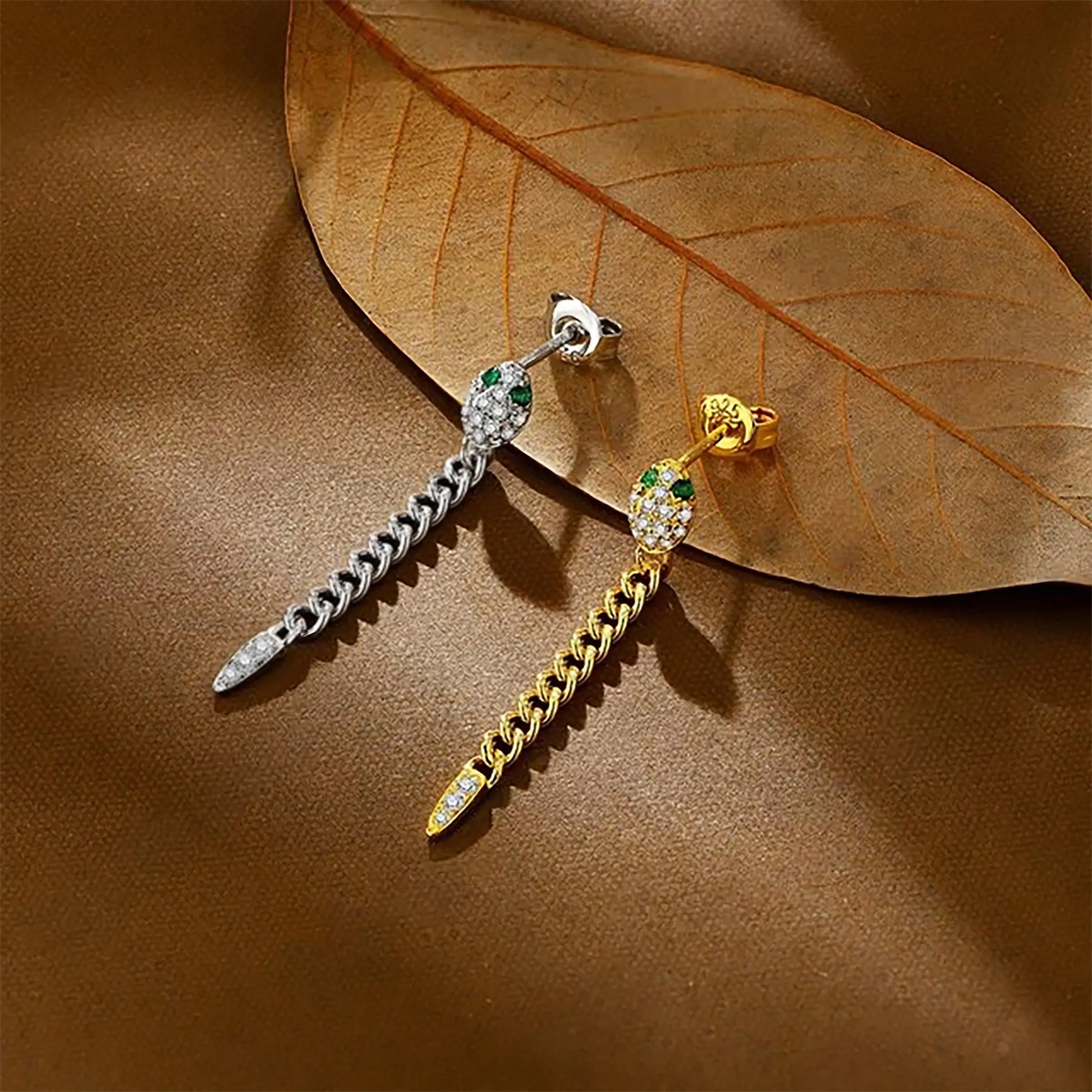 Yellow gold and white gold plated moissanite snake chain drop earrings with  green nano gemstones on a brown leaf background - Sensitive Stones
