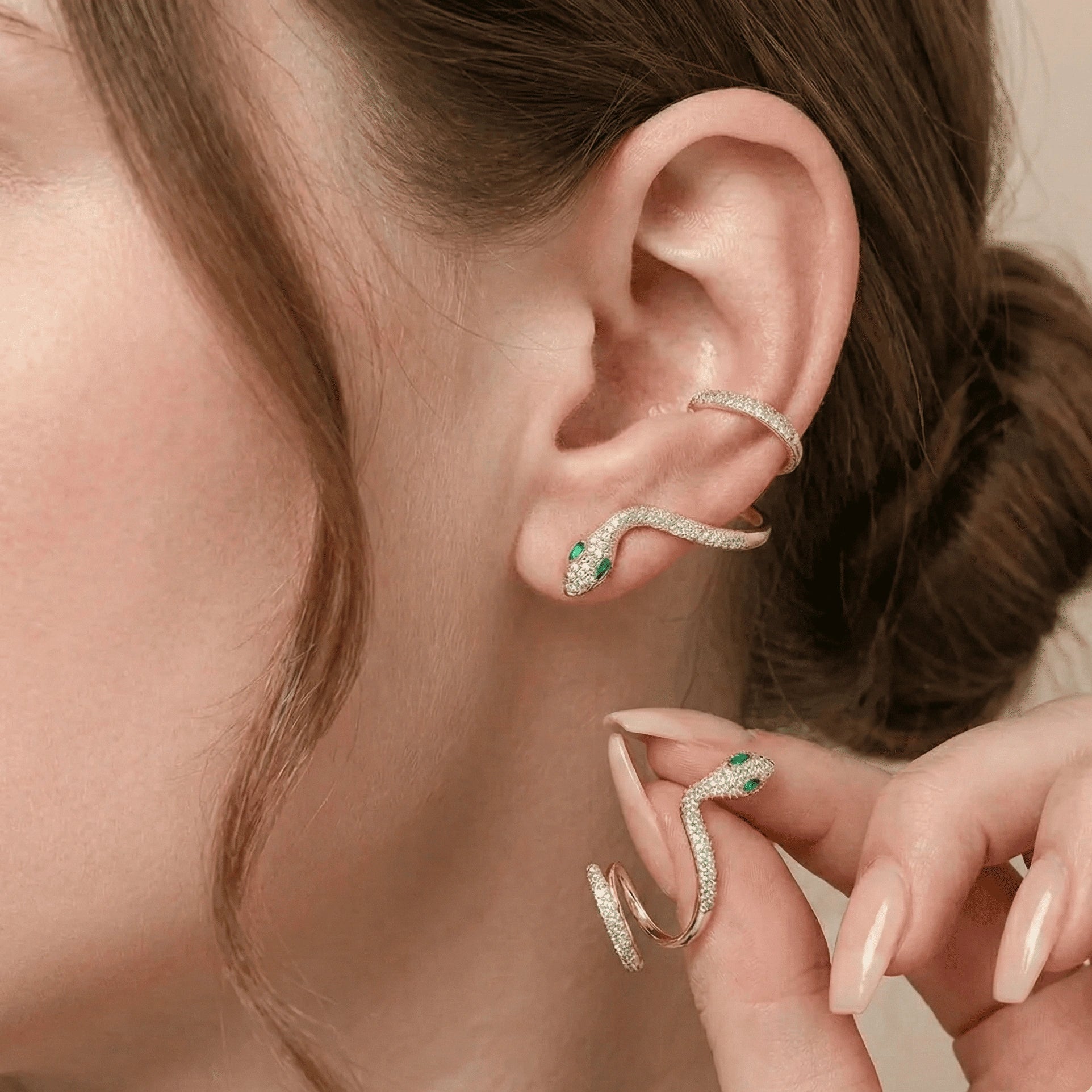 Close-up view of moissanite snake climber earrings with marquise-cut green nano gemstones and white moissanite sparkle, displaying refined sculptural detail on earlobe - Sensitive Stones