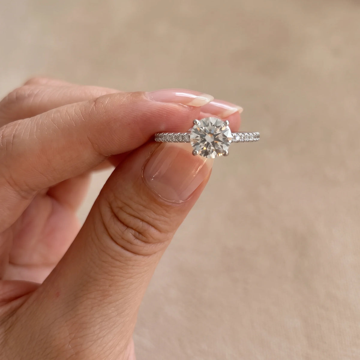Moissanite solitaire engagement ring held between fingertips showing the center stone raised above a 5A cubic zirconia pave band - Sensitive Stones