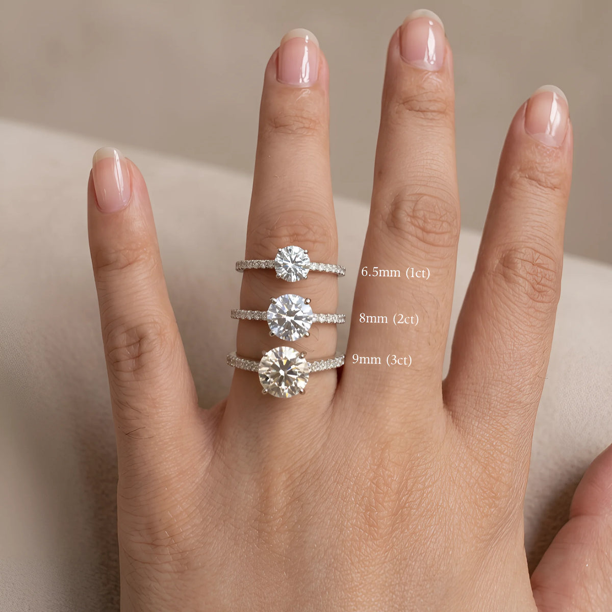 Size comparison of the moissanite solitaire engagement ring worn on hand showing the 6.5mm 1ct 8mm 2ct and 9mm 3ct center stones on 5A cubic zirconia pave bands - Sensitive Stones
