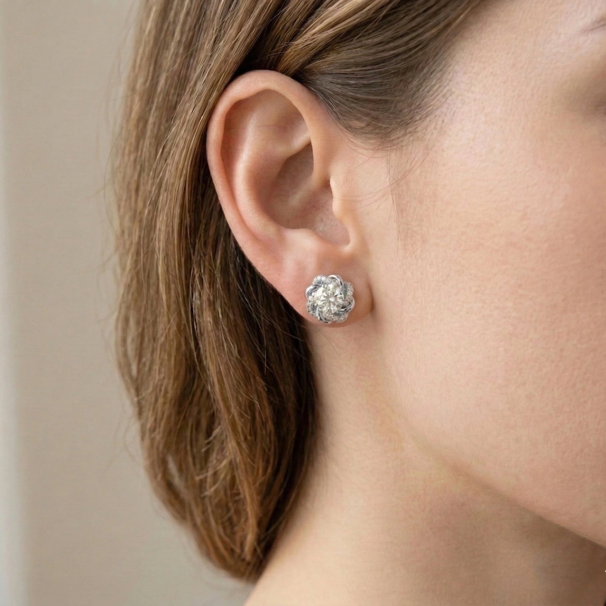 Woman wearing 1ct moissanite swirl flower stud earring in white gold plated 925 sterling silver with cubic zirconia pavé accents - Sensitive Stones