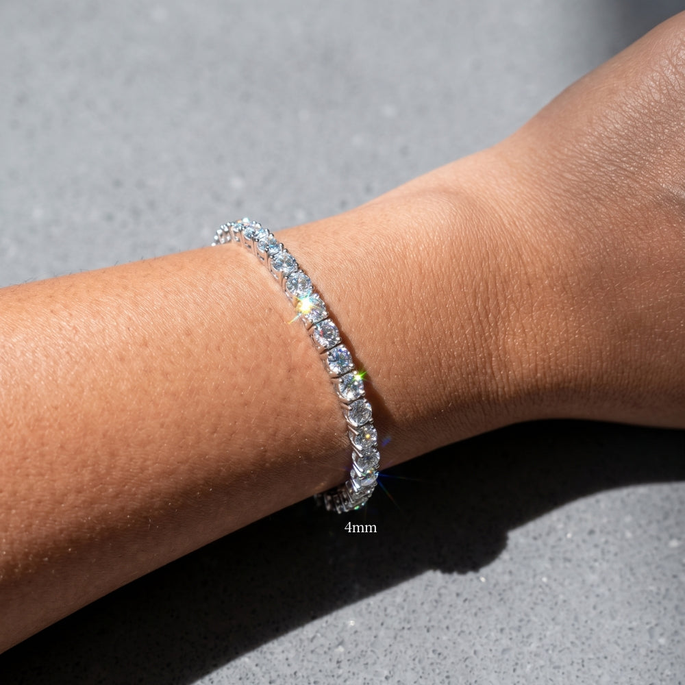 A close-up of a woman's wrist wearing a sparkling 4mm moissanite tennis bracelet in white gold plating, showing its natural rainbow flashes in bright sunlight - Sensitive Stones