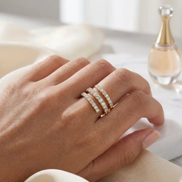 Yellow gold moissanite triple wrap spiral ring on hand with soft fabric and perfume bottle - Sensitive Stones