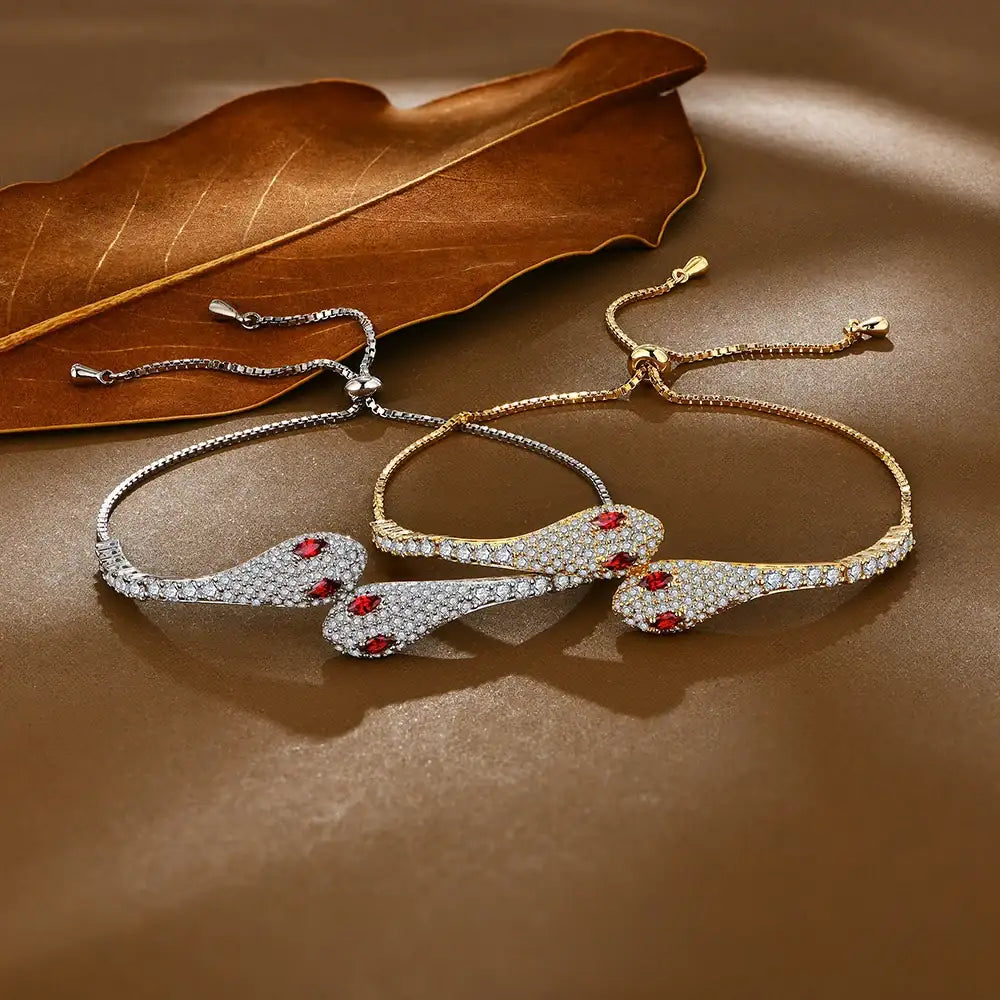Moissanite twin snake bracelets shown side by side in white gold and yellow gold finishes with red cubic zirconia eyes - Sensitive Stones