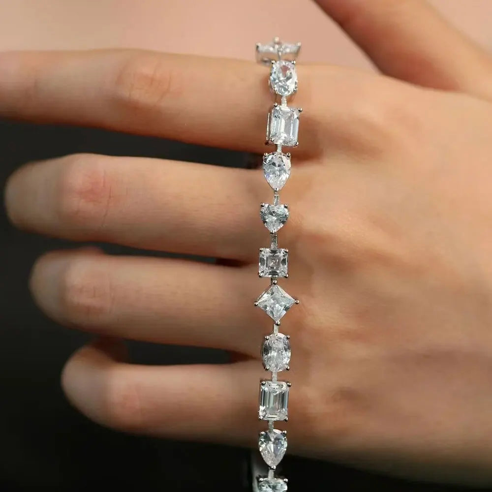 Close up of the multi shape moissanite tennis bracelet in white gold held across a hand, showing the oval, emerald cut, pear, heart and princess stone sequence - Sensitive Stones