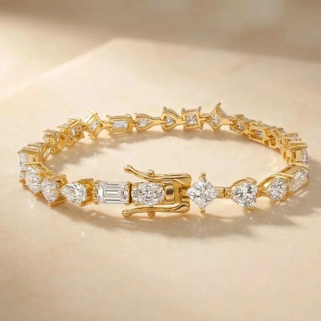 Multi shape moissanite tennis bracelet in yellow gold on a cream stone surface - Sensitive Stones