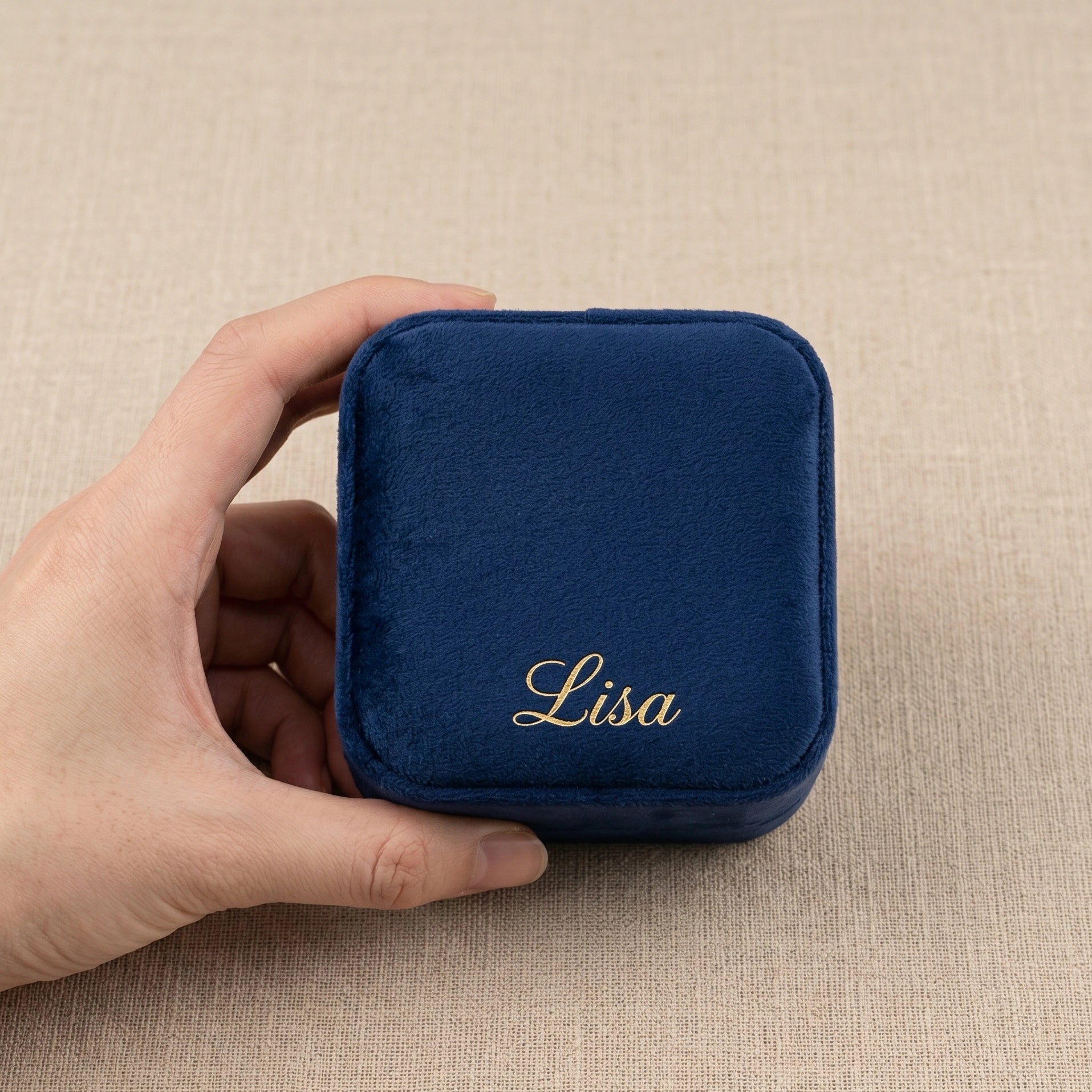 Hand holding navy blue personalized velvet travel jewelry box with gold engraved name - Sensitive Stones