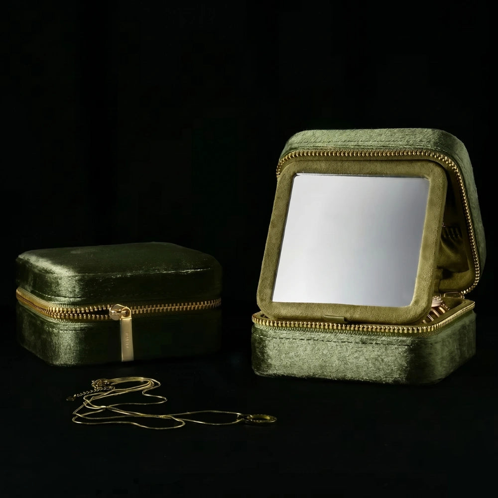 Olive green velvet travel jewelry box open showing built-in mirror with gold necklace beside it on dark background - Sensitive Stones