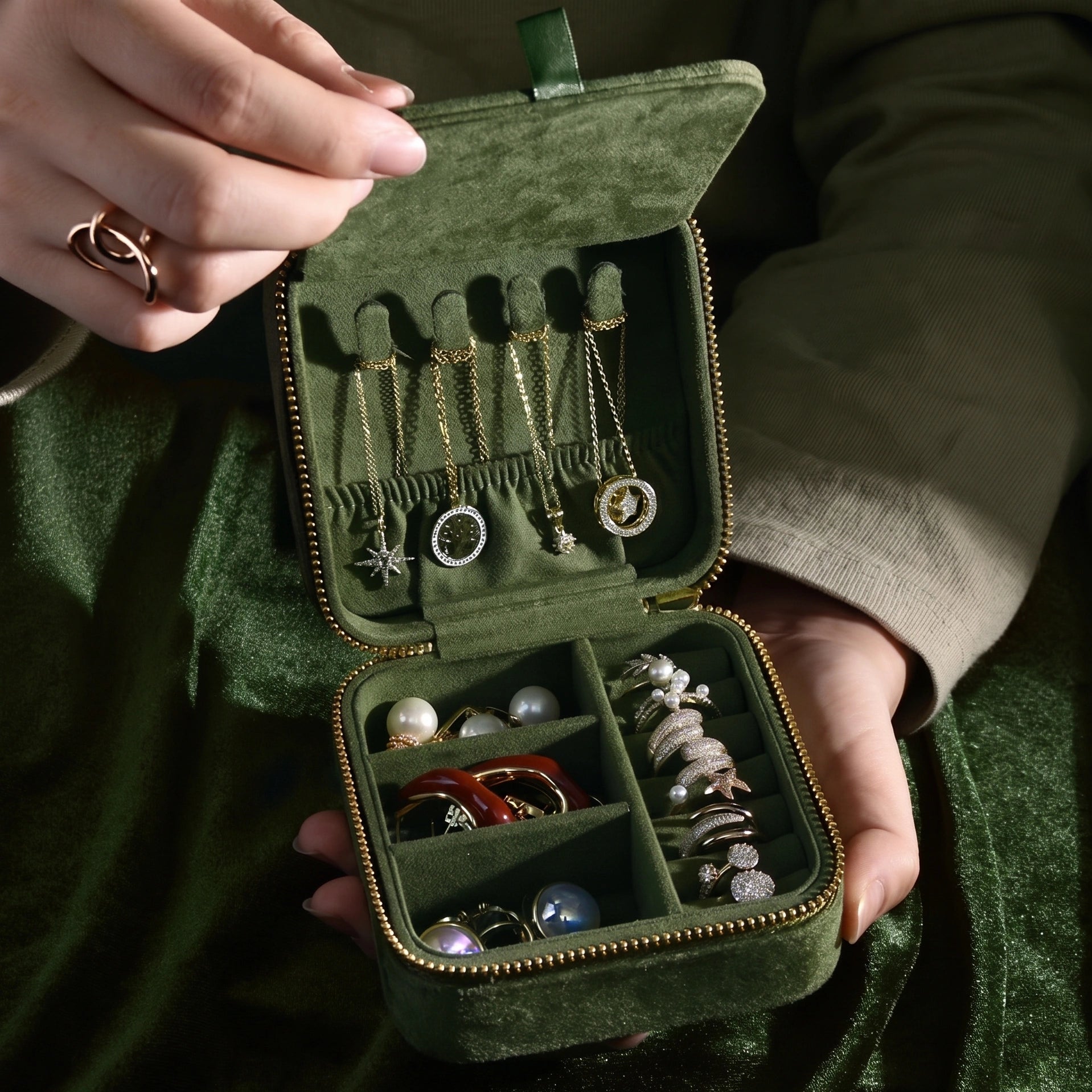 Olive green velvet travel jewelry box held open showing necklace hooks with gold necklaces and rings stored in compartments - Sensitive Stones