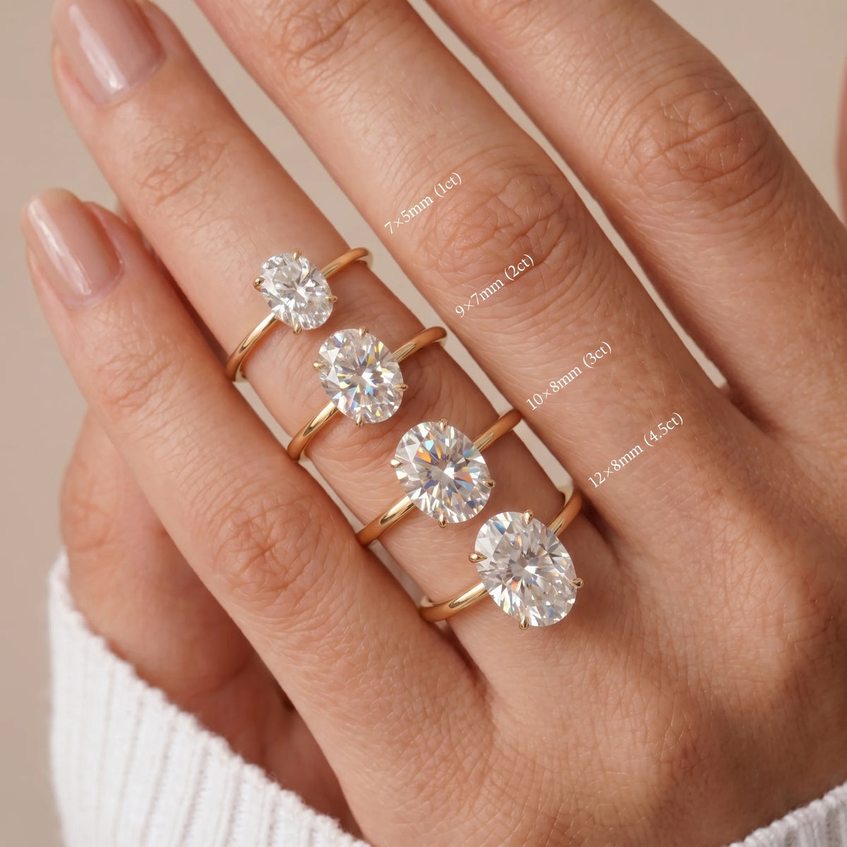 All four oval stone sizes of the moissanite solitaire ring worn on a hand in a yellow gold finish showing 7×5mm (1ct), 9×7mm (2ct), 10×8mm (3ct) and 12×8mm (4.5ct) - Sensitive Stones