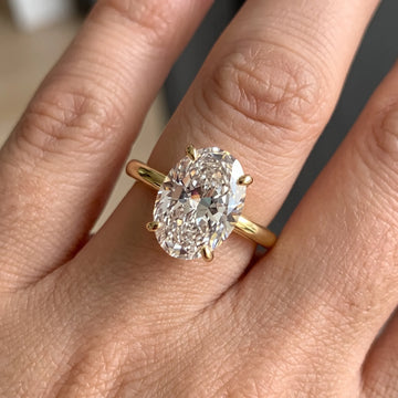 Close-up of a hand wearing the oval cut moissanite solitaire ring in a yellow gold finish - Sensitive Stones