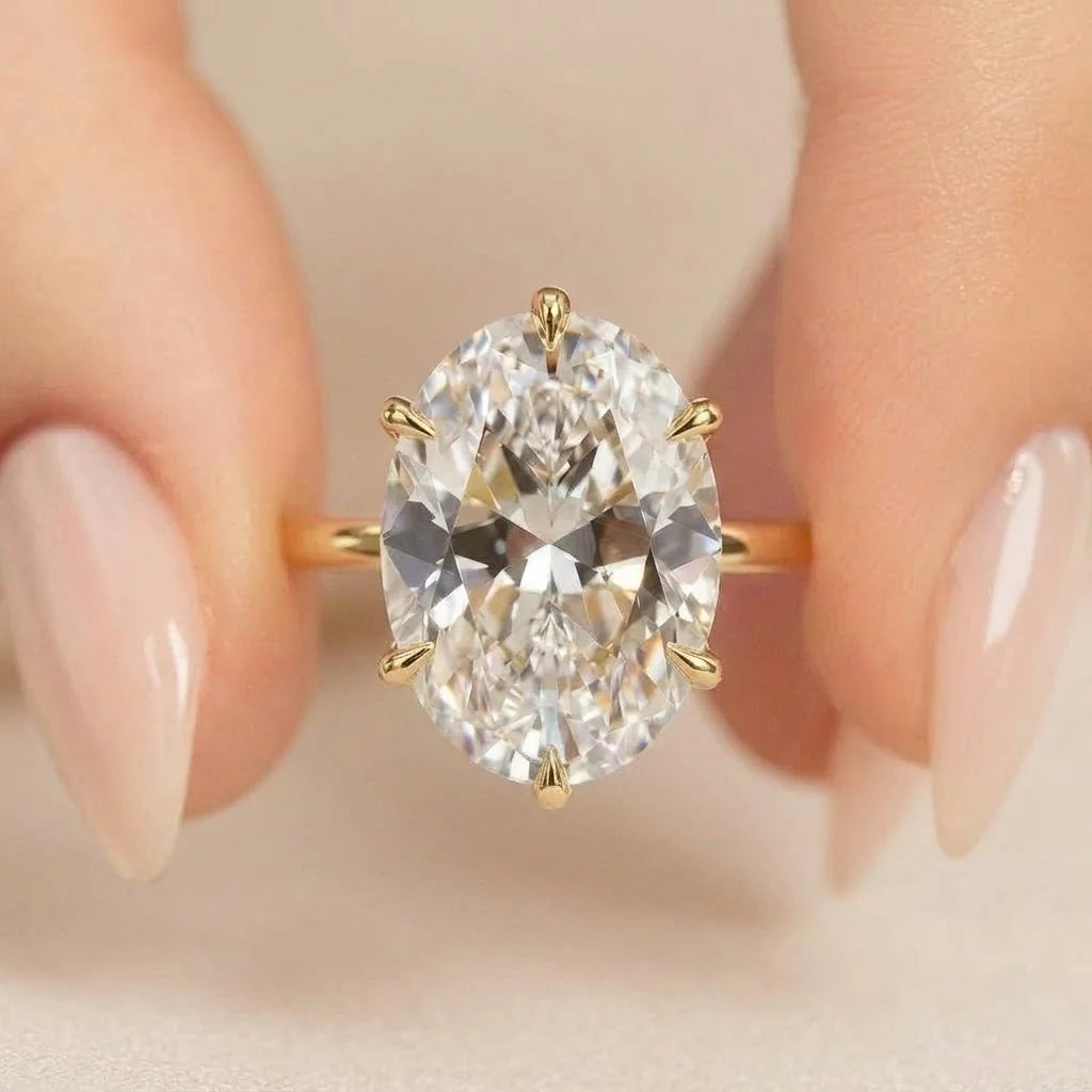 2ct oval moissanite engagement ring in 14K gold filled resting on blush satin