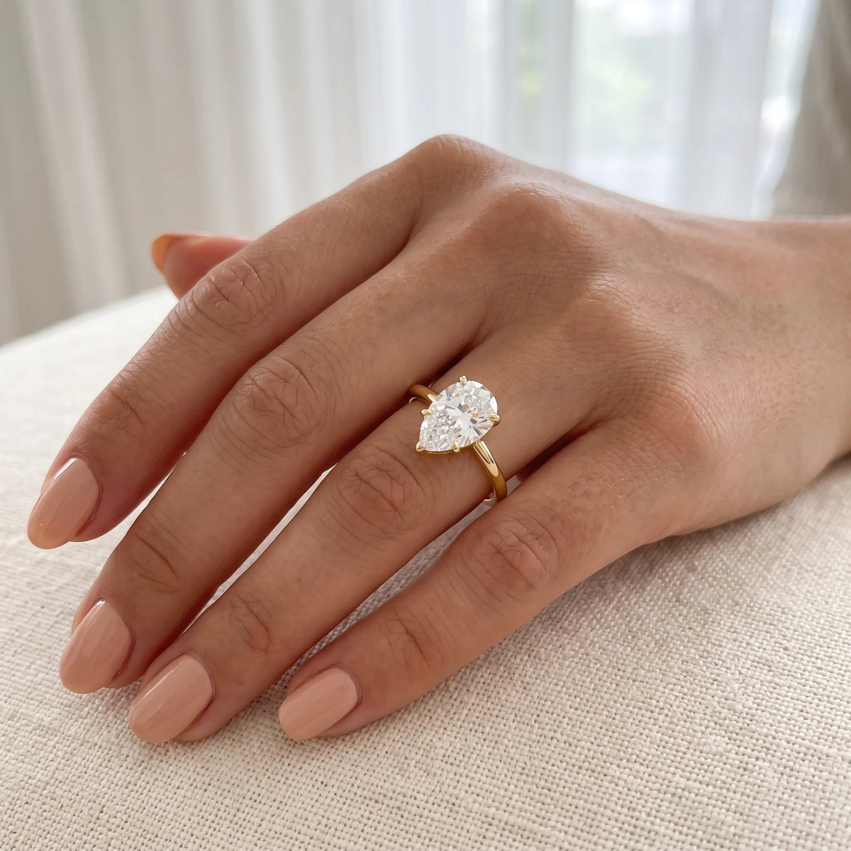 Pear cut moissanite engagement ring in 14K gold filled worn on the hand, the 10x7mm pear set with its point towards the fingertip - Sensitive Stones