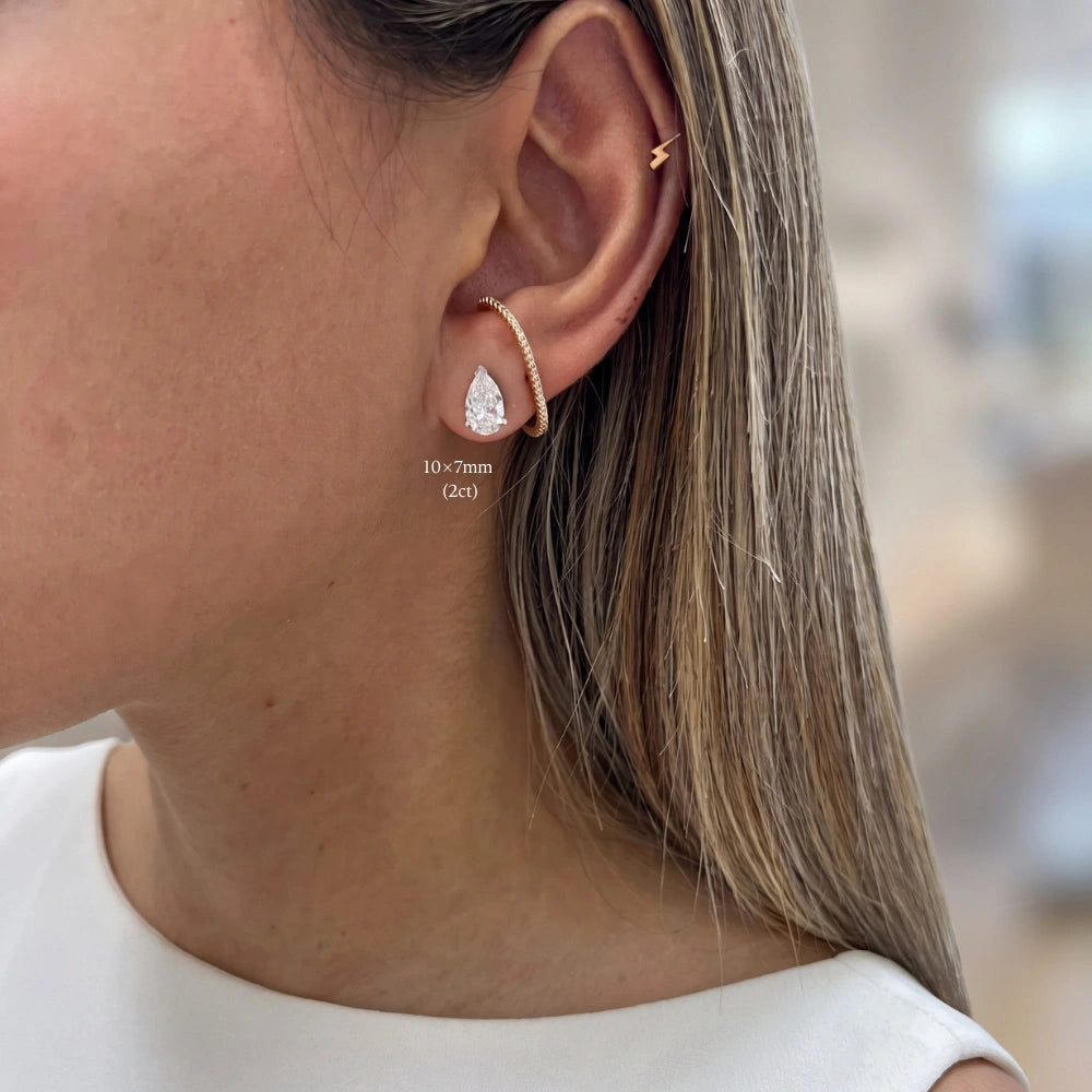 Woman wearing a 2ct white gold pear cut moissanite stud point up in a lobe piercing