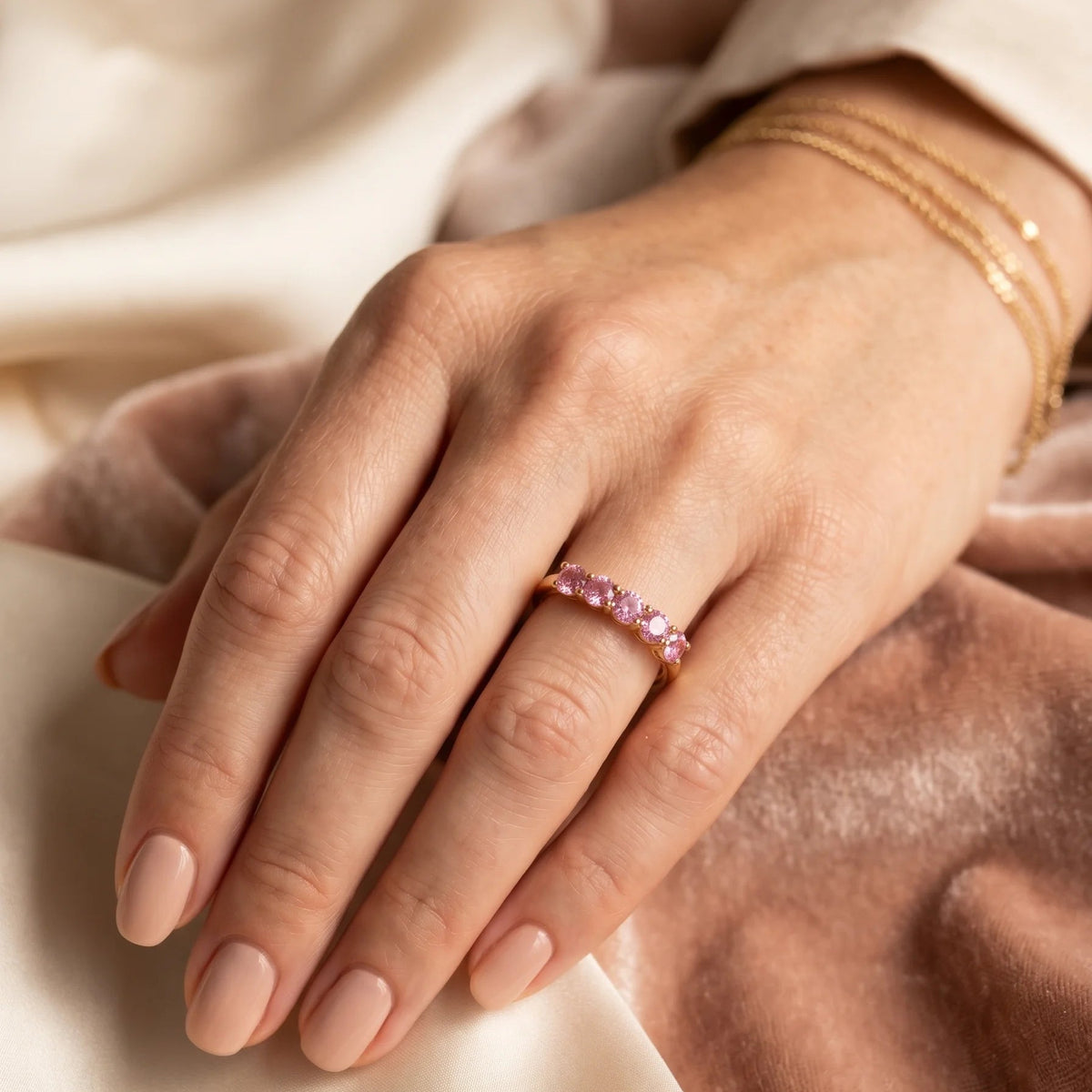 Pink moissanite five stone stackable ring in 14K gold filled worn on a hand, five 3.5mm pink stones in a close row across the finger - Sensitive Stones