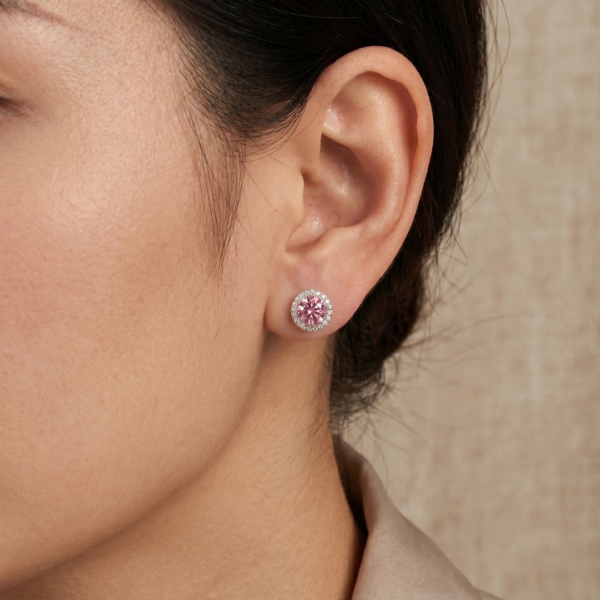 Woman wearing 1ct pink moissanite halo stud earrings in 925 sterling silver showing natural size on ear - Sensitive Stones