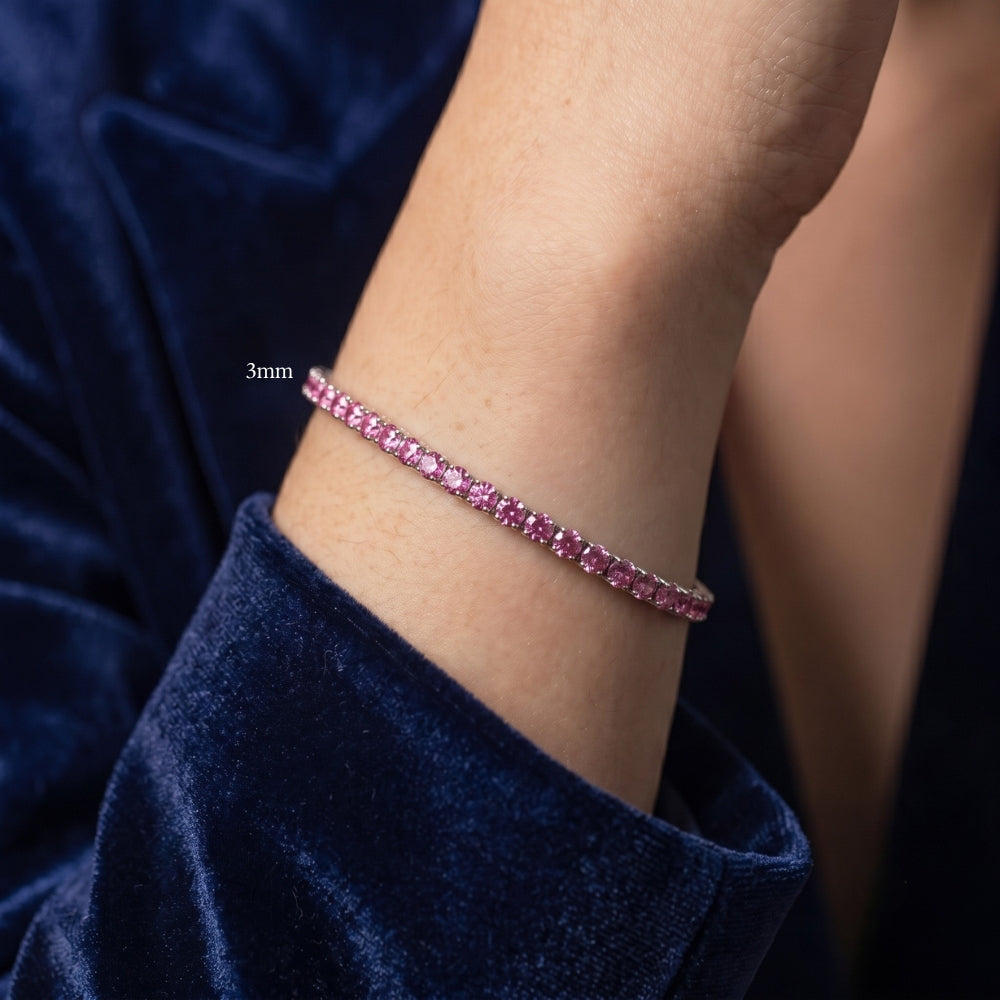 Woman's wrist wearing a 3mm pink moissanite tennis bracelet in white gold plated sterling silver, styled with navy velvet - Sensitive Stones