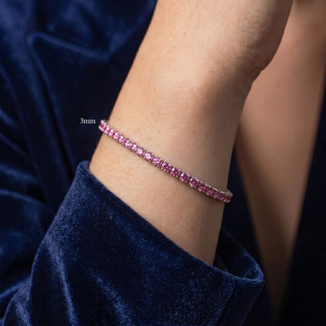 Woman's wrist wearing a 3mm pink moissanite tennis bracelet in white gold plated sterling silver, styled with navy velvet - Sensitive Stones