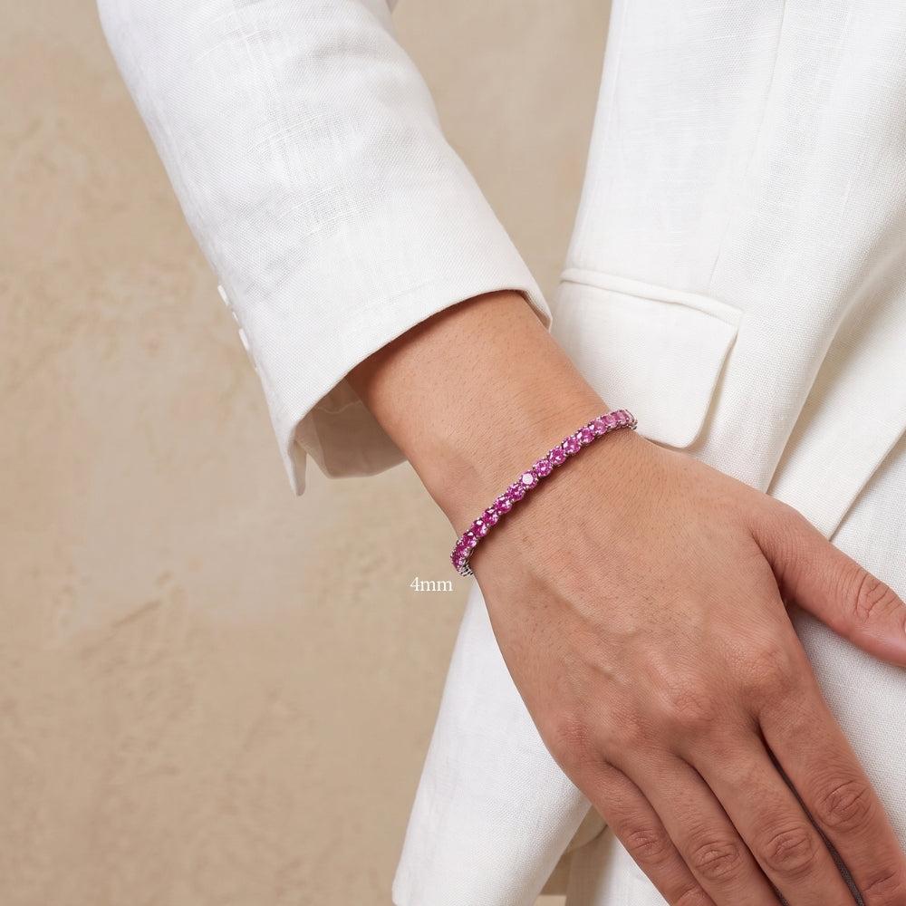4mm pink moissanite tennis bracelet in white gold plated sterling silver worn on a woman's wrist with a white blazer - Sensitive Stones