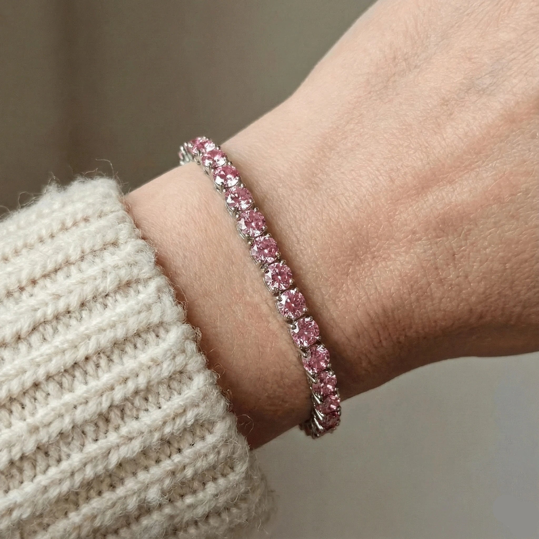 Pink moissanite tennis bracelet with 8 Hearts & 8 Arrows precision cut stones in sterling silver 4-prong setting, worn with cream knit sweater - Sensitive Stones