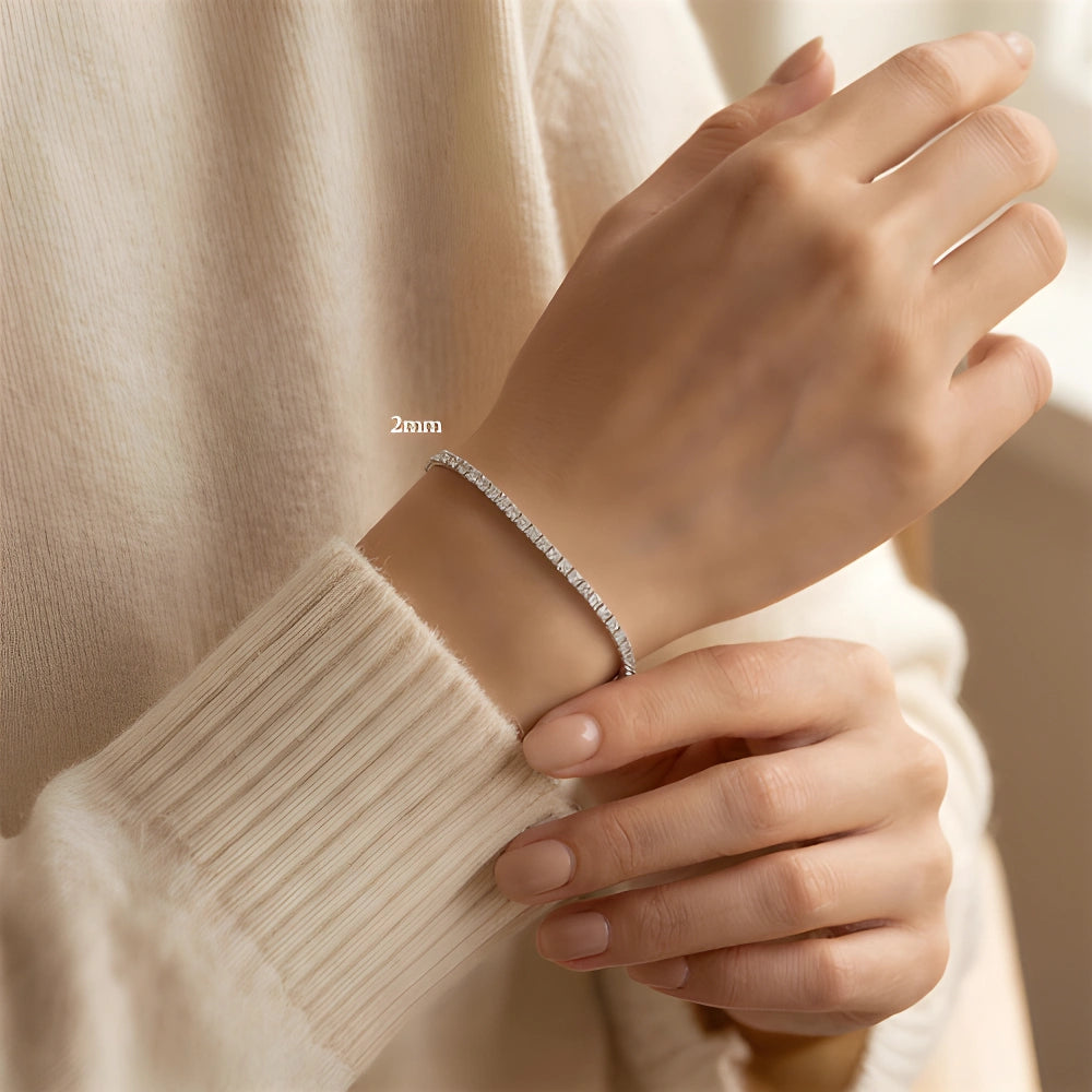 Woman wearing a 2mm princess cut moissanite tennis bracelet, wrist resting on a cream cashmere sleeve - Sensitive Stones