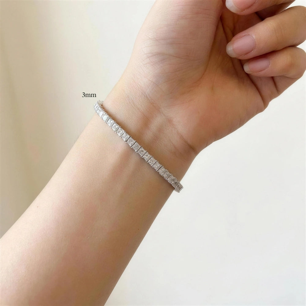 Woman wearing a 3mm princess cut moissanite tennis bracelet against a soft cream minimalist background - Sensitive Stones 