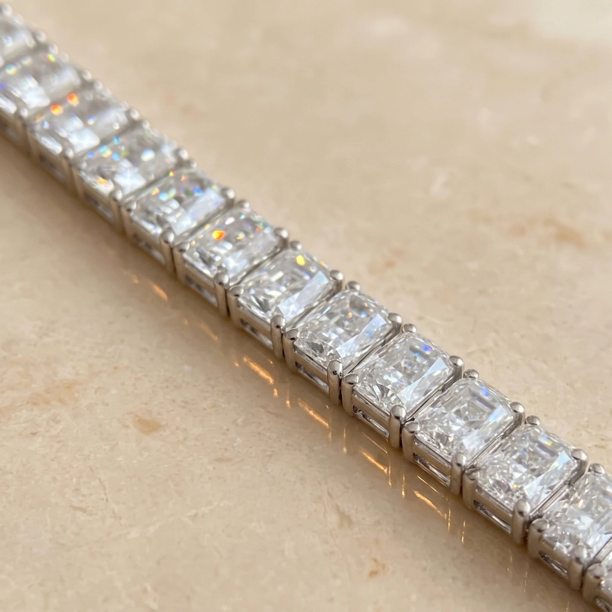 Rainbow fire and brilliance across the radiant cut moissanite stones of a sterling silver tennis bracelet