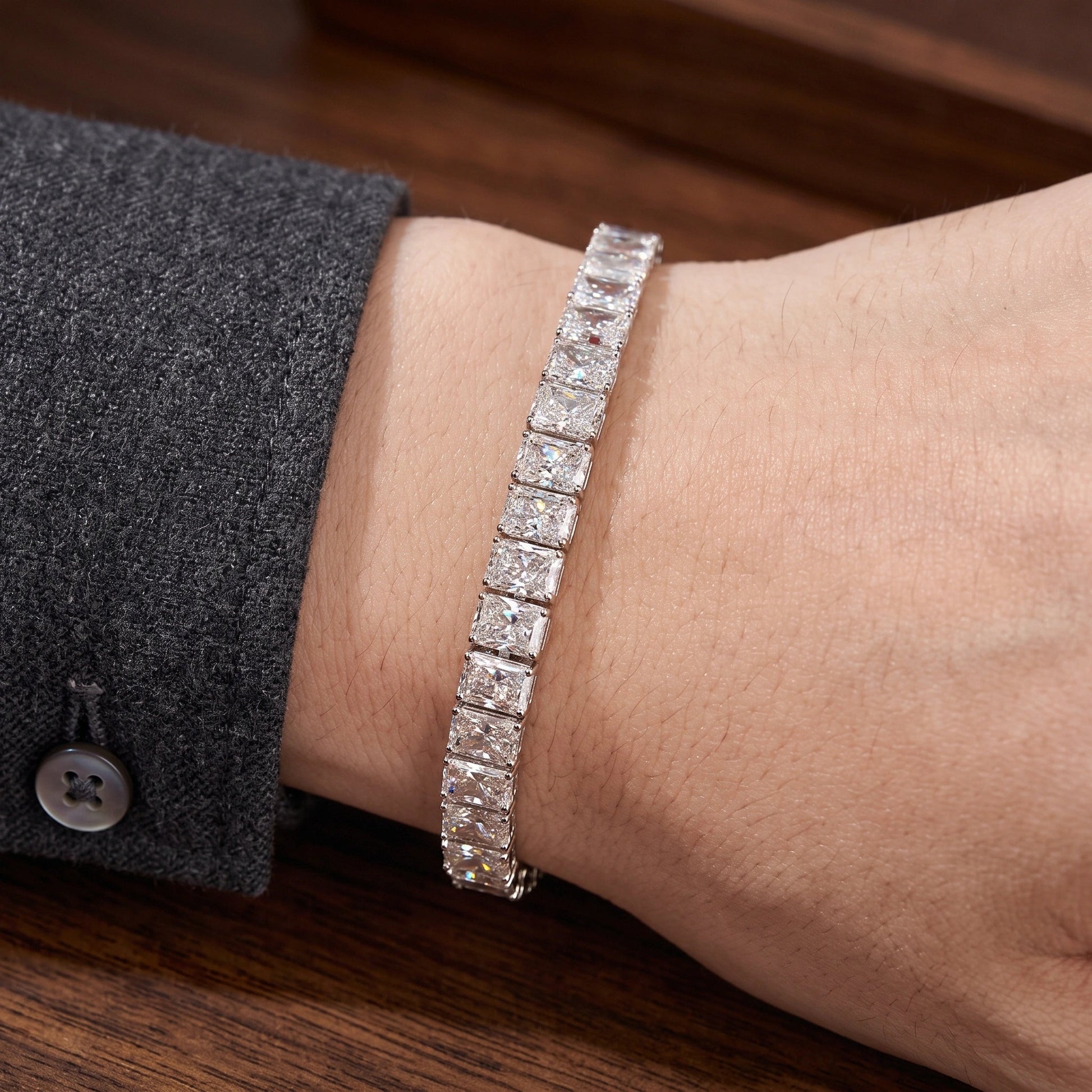 Radiant cut moissanite tennis bracelet worn on the wrist with a tailored blazer cuff