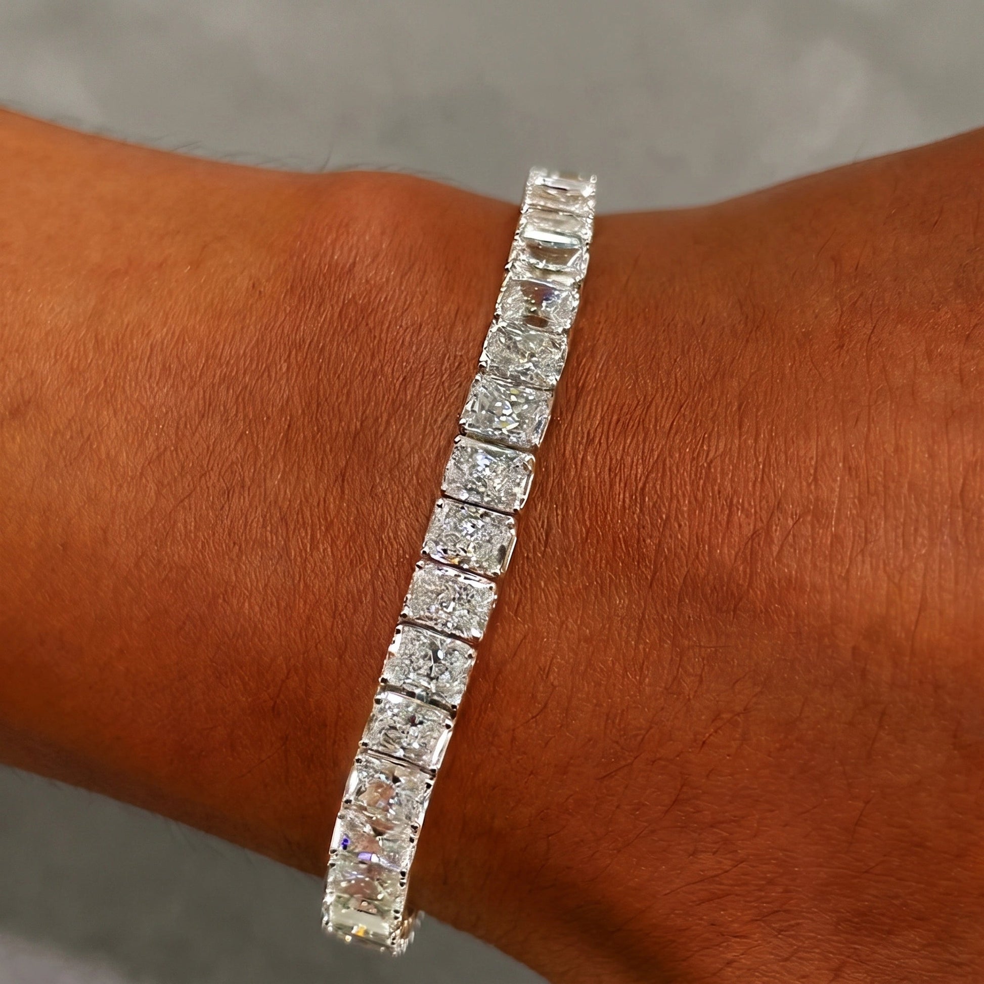 Radiant cut moissanite tennis bracelet worn on the wrist, 5mm wide in 925 sterling silver