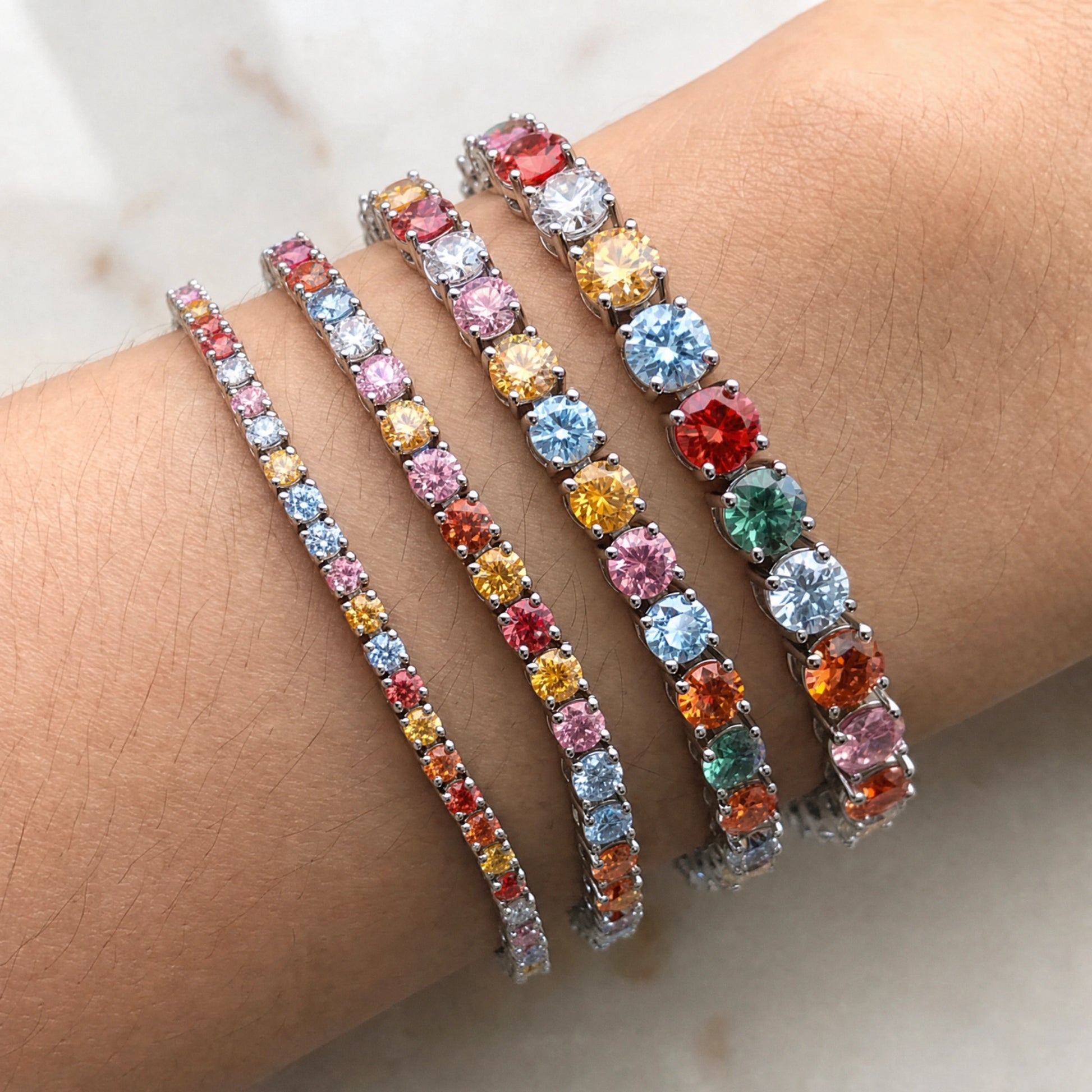 Rainbow moissanite tennis bracelet stone size comparison, 3mm, 4mm, 5mm and 6.5mm worn on wrist - Sensitive Stones