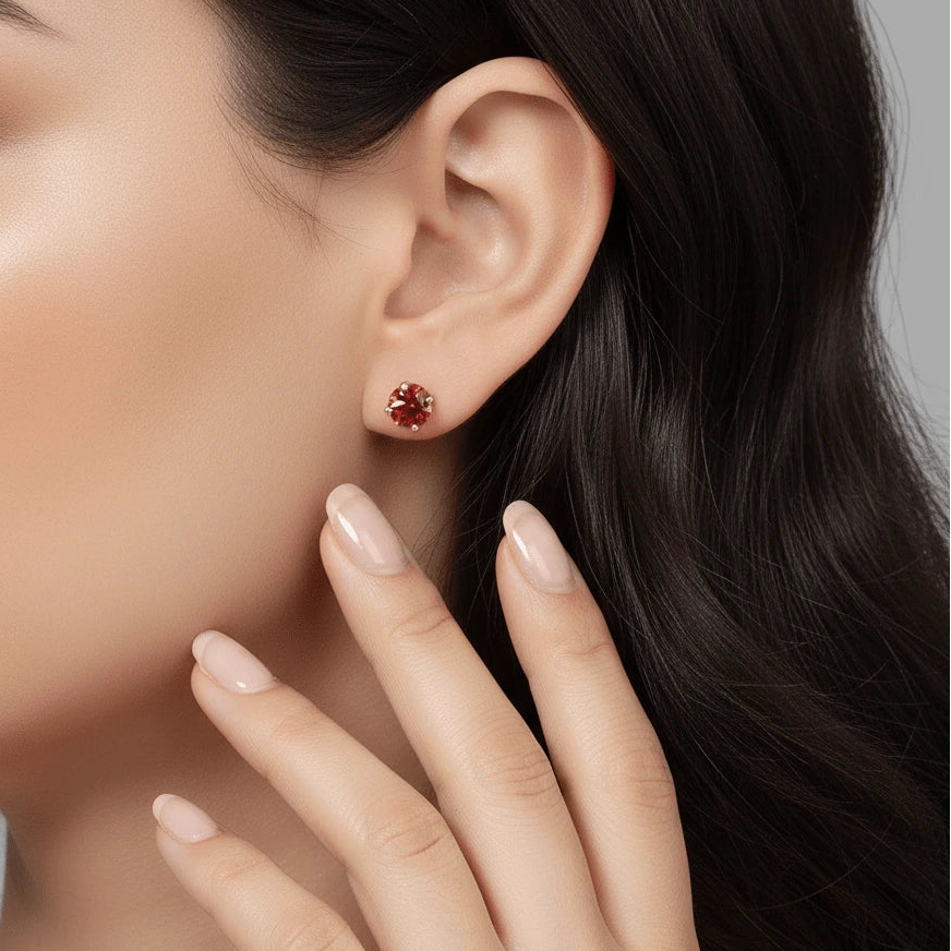 Close-up of a red moissanite stud earring worn on a woman's ear, round cut, 4-prong setting - Sensitive Stones