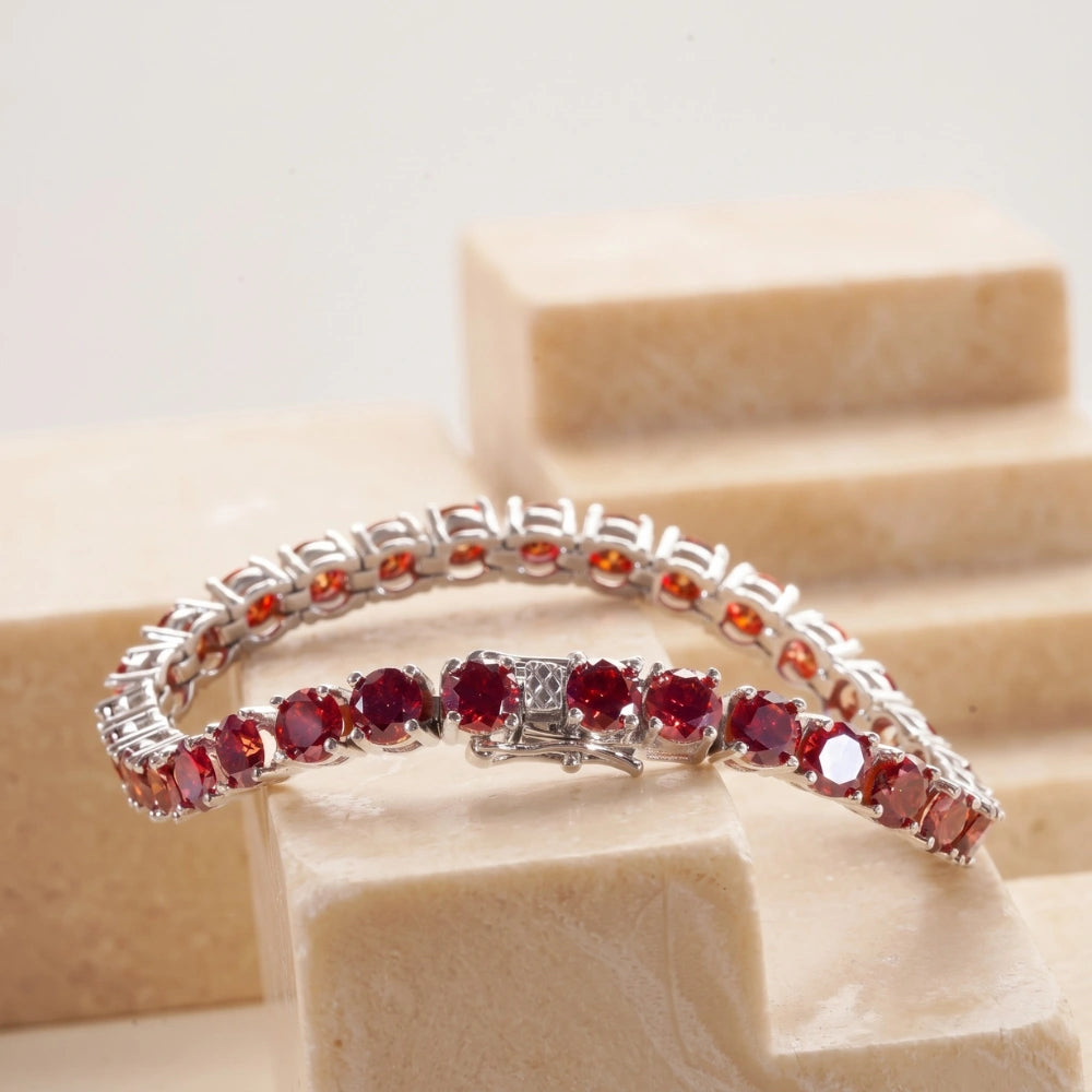 Red moissanite tennis bracelet in white gold plated sterling silver displayed on a marble surface - Sensitive Stones