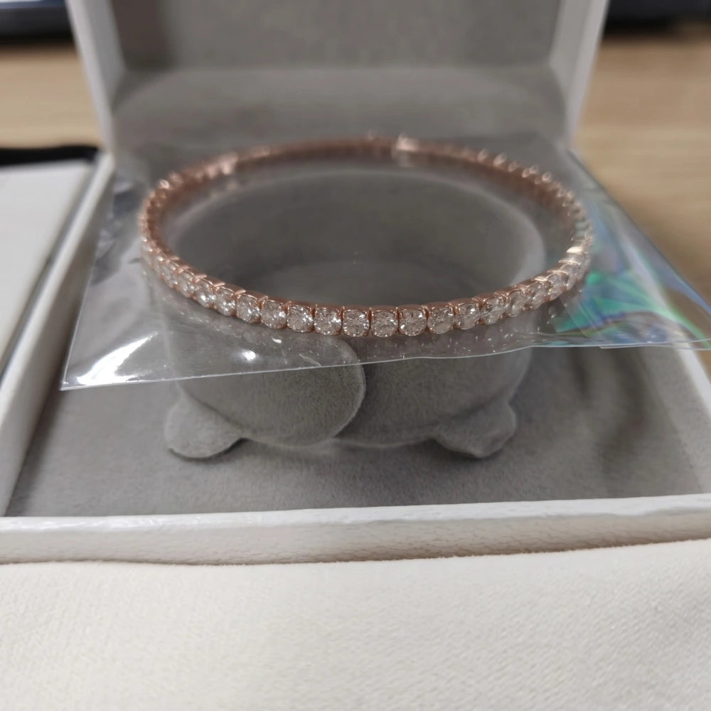 A rose gold stretch moissanite tennis bracelet with clear stones, displayed inside an open white jewelry box on a gray cushion - Sensitive Stones