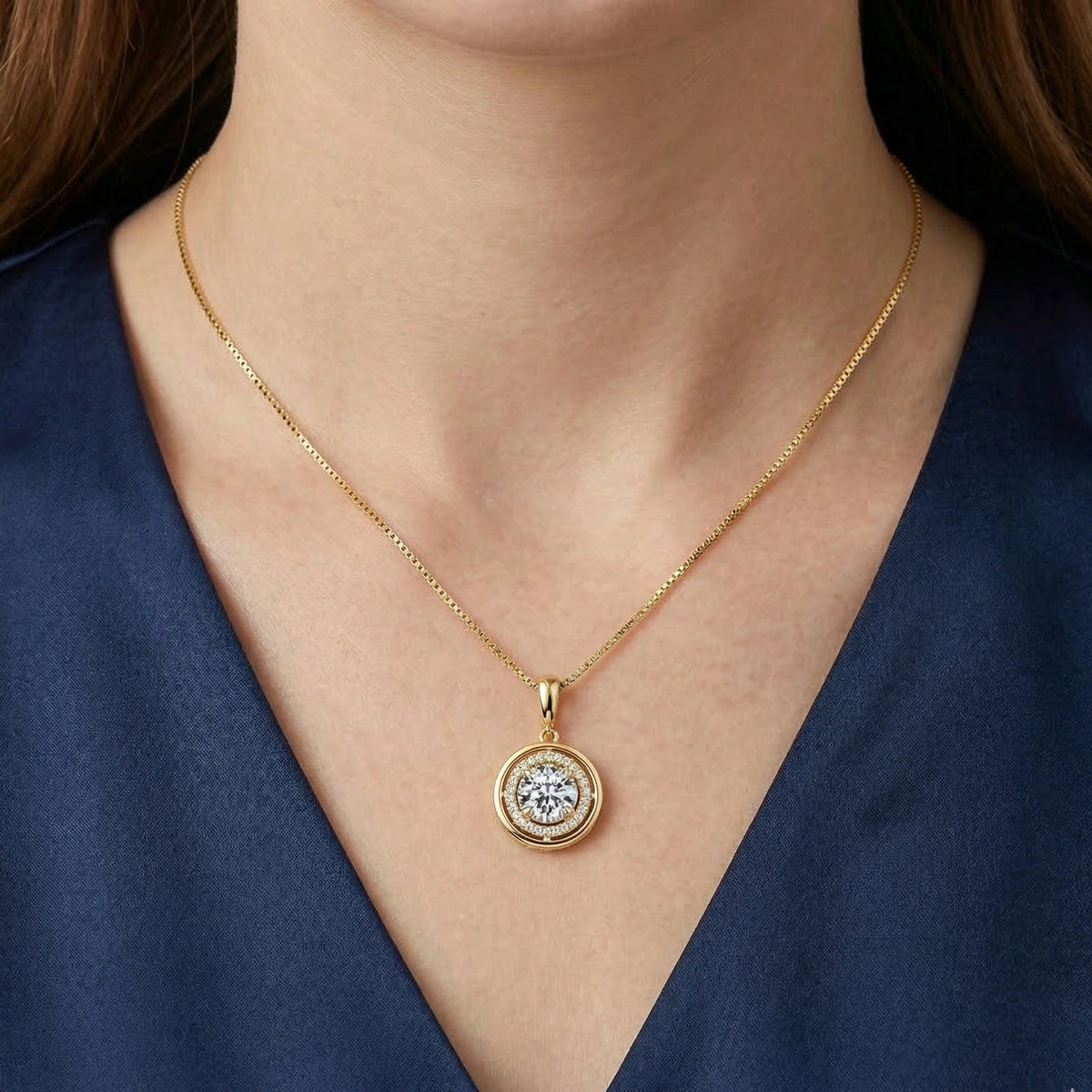 Woman wearing a round moissanite halo pendant necklace in a yellow gold finish with a navy top - Sensitive Stones