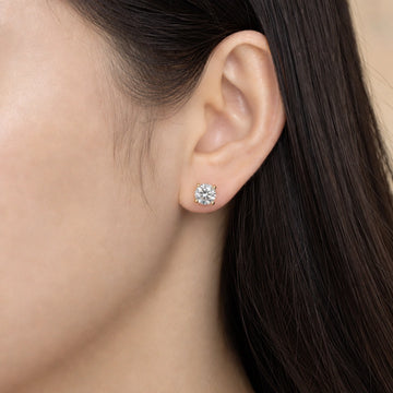 Woman wearing screw back moissanite stud earring, 1ct round with 18K yellow gold prongs on ear - Sensitive Stones