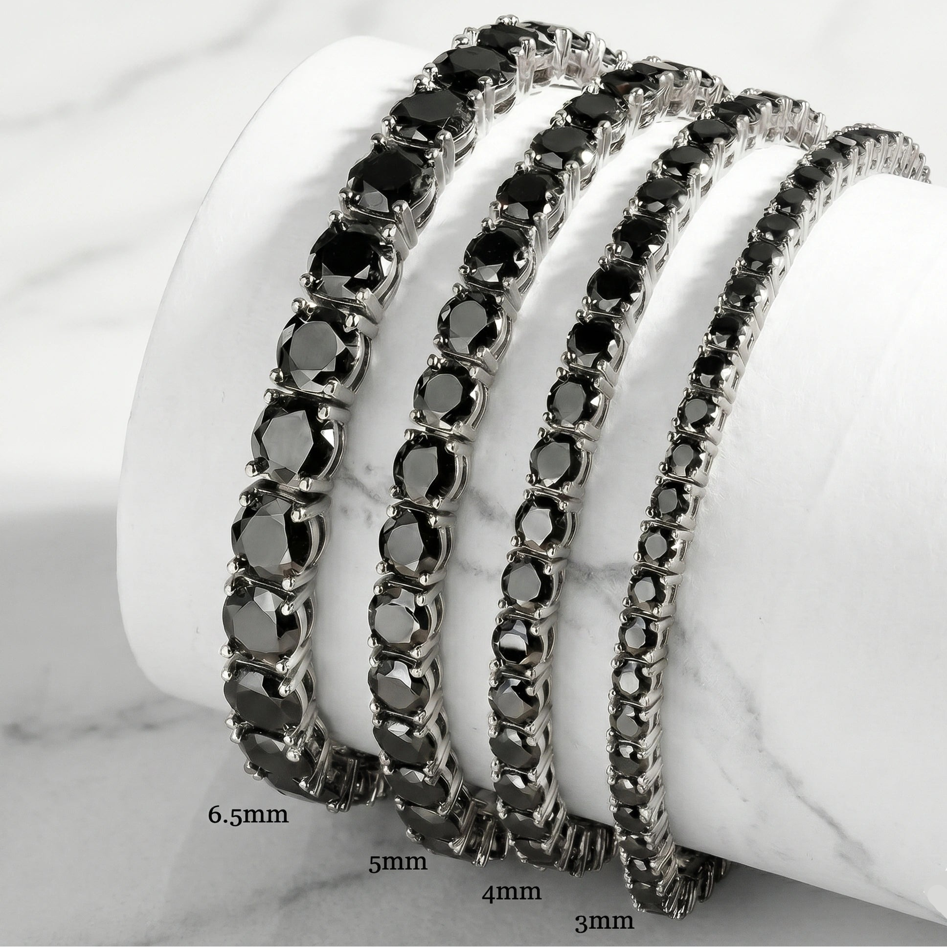 Set of black moissanite tennis bracelets in white gold plating on a white stand with sizes 3mm, 4mm, 5mm, 6.5mm - Sensitive Stones