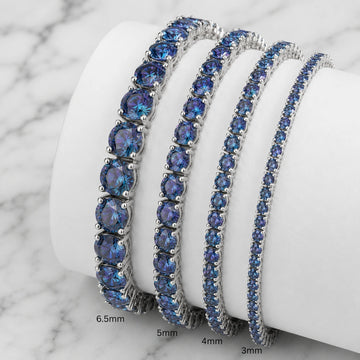 Set of blue moissanite tennis bracelets in black gold plating on a white stand with sizes 3mm, 4mm, 5mm, 6.5mm - Sensitive Stones