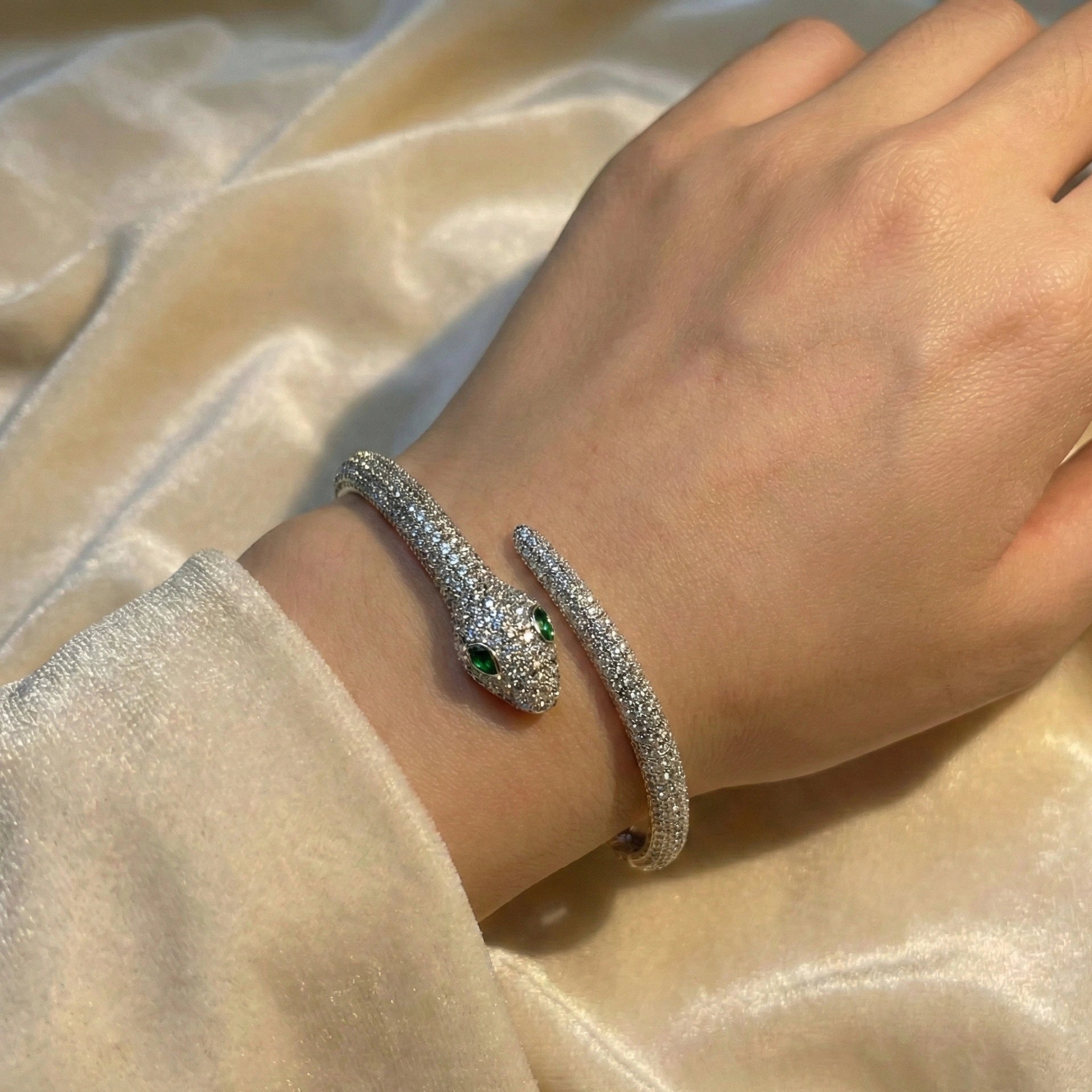 Moissanite snake bracelet on model’s wrist, coiling elegantly in 925 sterling silver with 18K white gold plating, D VVS1 moissanite pavé and green emerald accents - Sensitive Stones