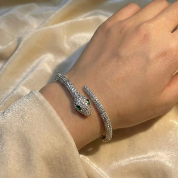Woman wearing the moissanite snake bracelet in a white gold finish, the pavé serpent wrapped around her wrist with its head crossing over its tail - Sensitive Stones