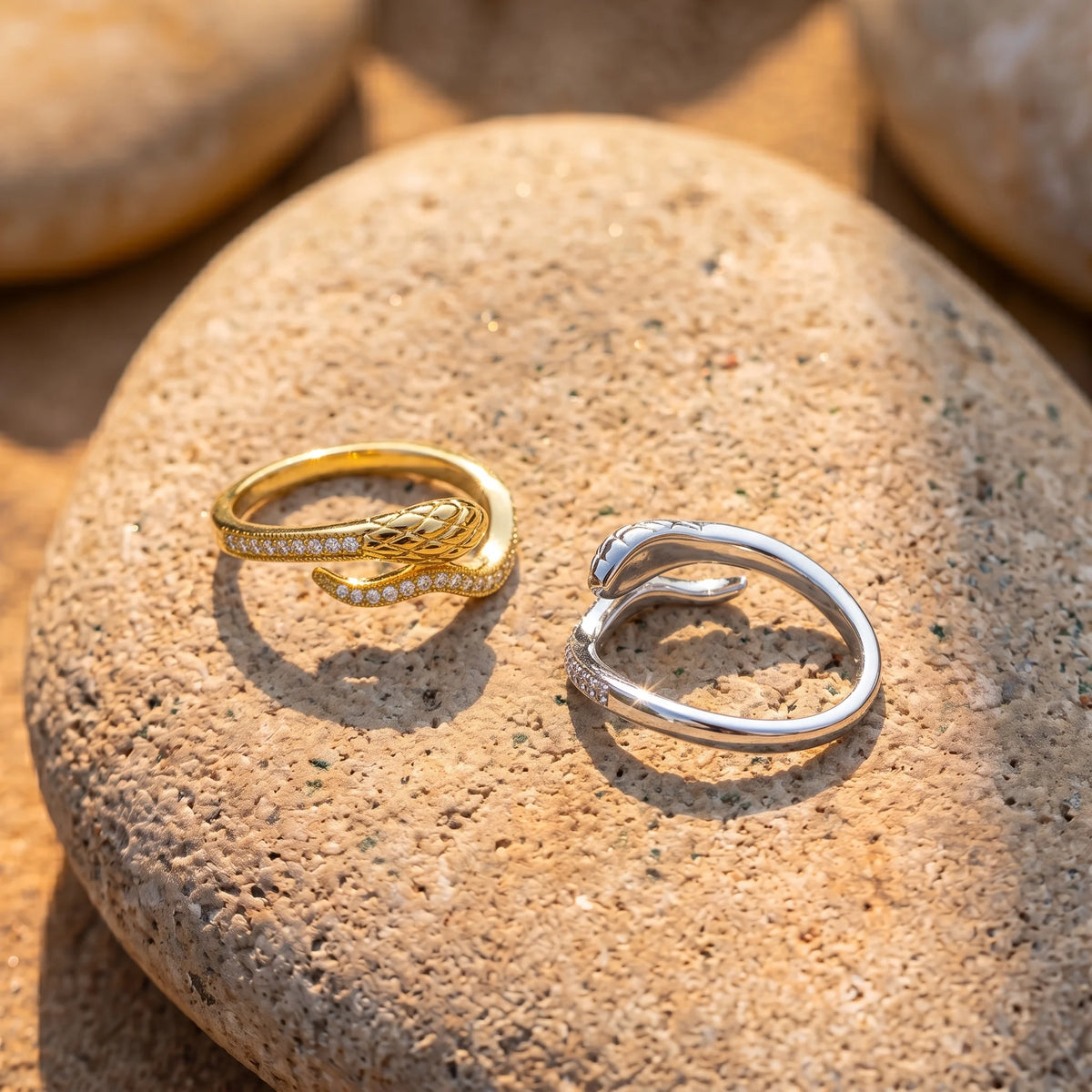 Snake half eternity moissanite rings in yellow gold and white gold finishes side by side on a stone - Sensitive Stones