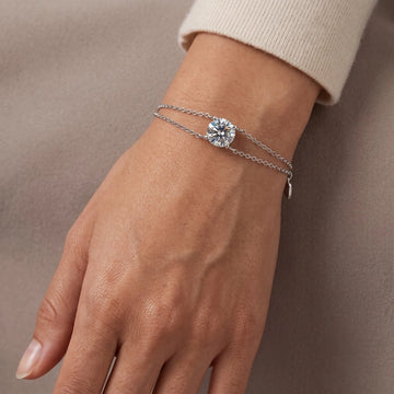 A woman's wrist wearing a white gold moissanite solitaire double chain bracelet with a single round 1ct D color stone - Sensitive Stones